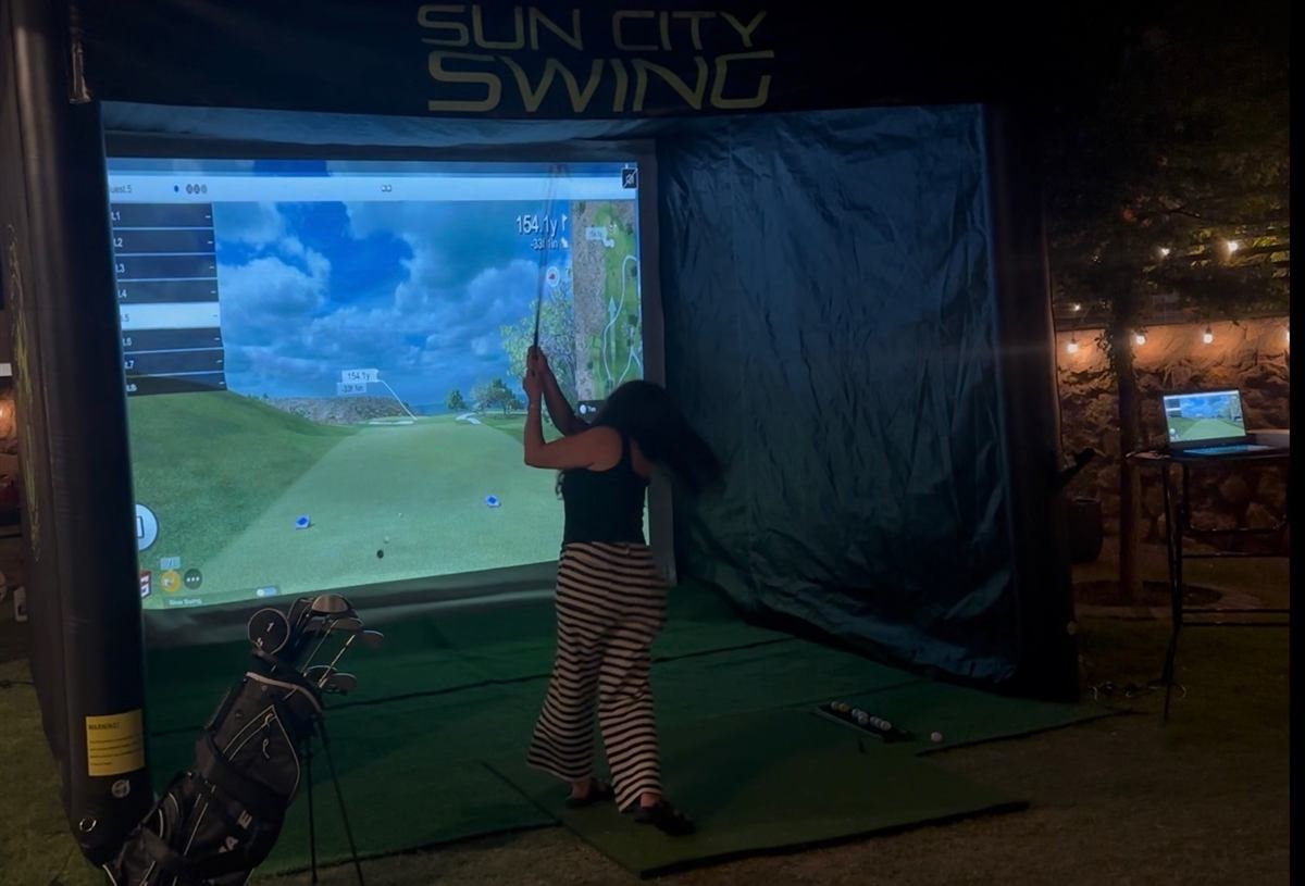 Sun City Swing mobile golf simulator set up at an evening backyard event